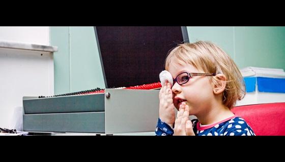A young girl taking a vison test by covering one eye