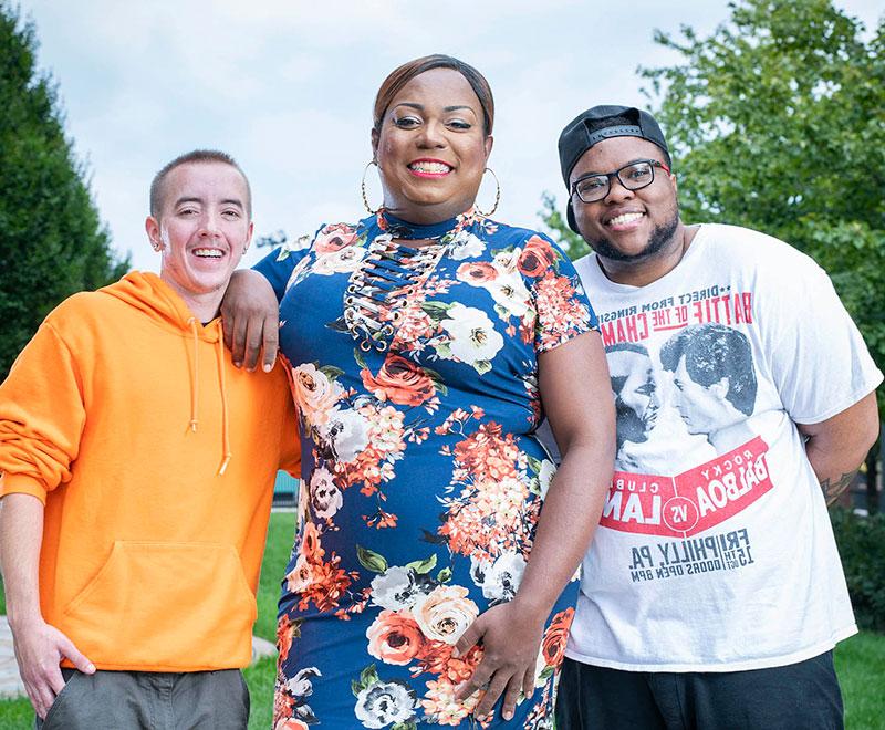 three transgender patients pose outside together, smiling