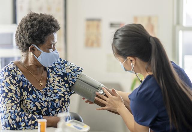 a nurse taking a woman's blood pressure